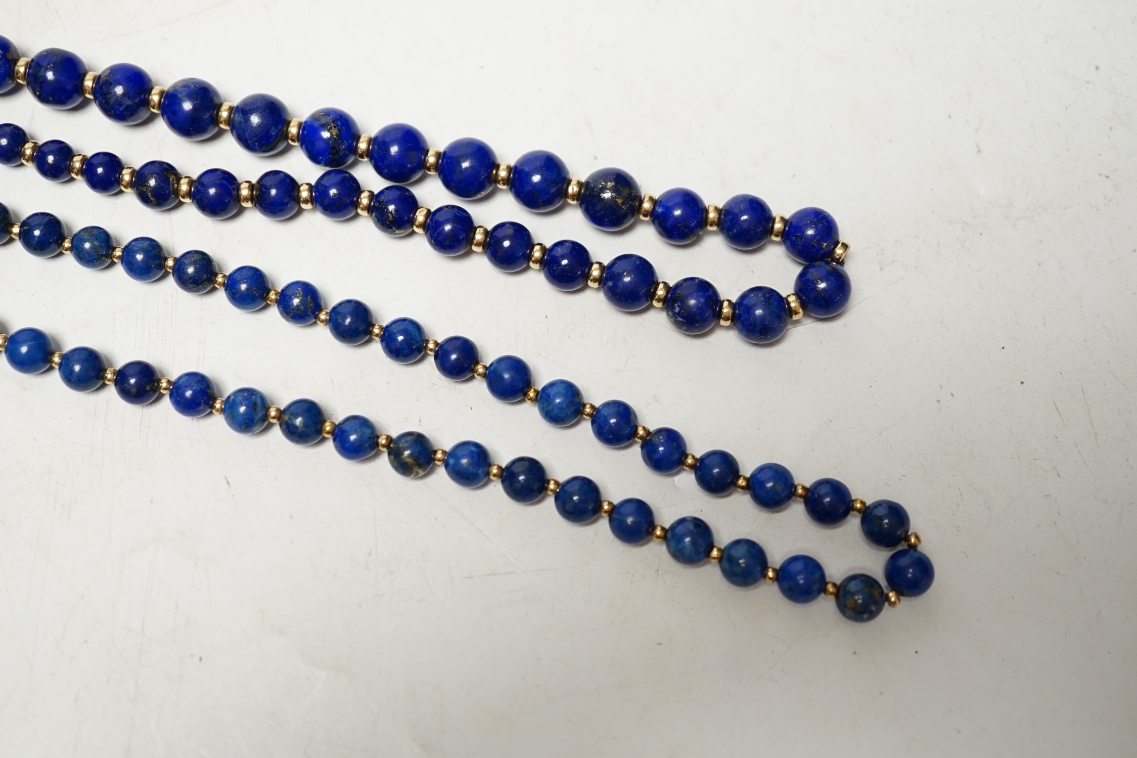 Two lapis lazuli bead necklaces with yellow metal spacers, largest 76cm and a pair of earrings. Condition - fair